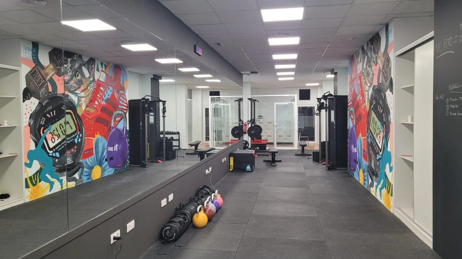 Sala de entrenamiento de ALDIFIT Benlloch con mural, pesas y zona de fuerza